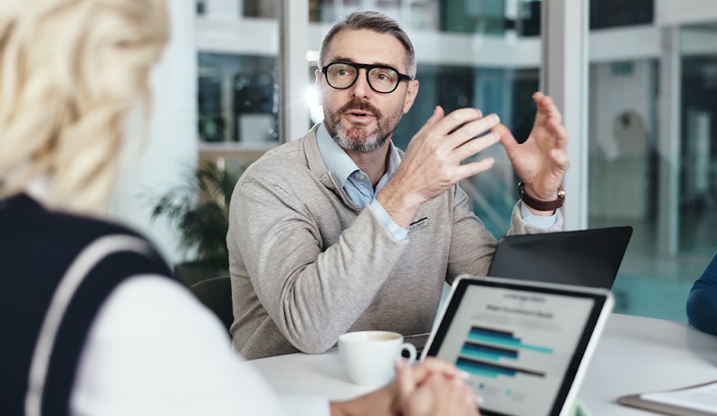 AR AP Automation Strategy Discussed in Team Meeting A man explaining AR AP automation concepts during a business meeting with laptops and charts on display.