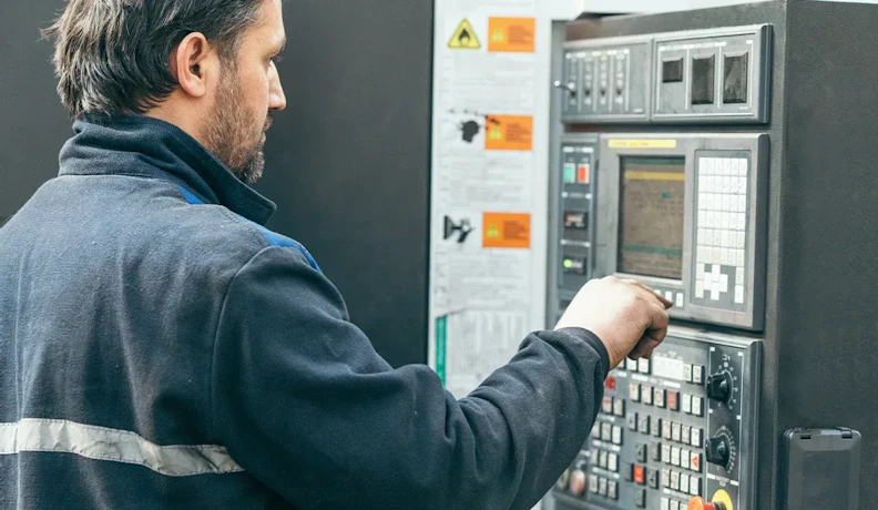 CNC operator sets machine controls during production CNC machine operator adjusting control panel on the factory floor
