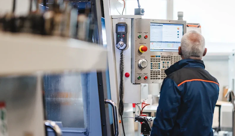 CNC operator adjusting machine controls on the shop floor Operator using a CNC machine control panel on a factory shop floor