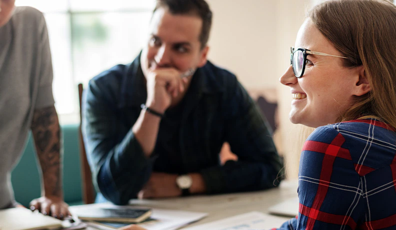 Cost of Delaying Digital Transformation in Team Strategy Smiling woman in glasses leads a team discussion, highlighting the impact of delaying digital transformation initiatives.