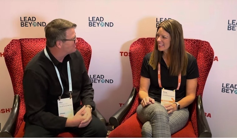 ECI e-automate Cloud ERP Interview at LEAD Beyond Two professionals discussing ECI e-automate cloud ERP during a LEAD Beyond event, seated in red chairs with branded backdrop.