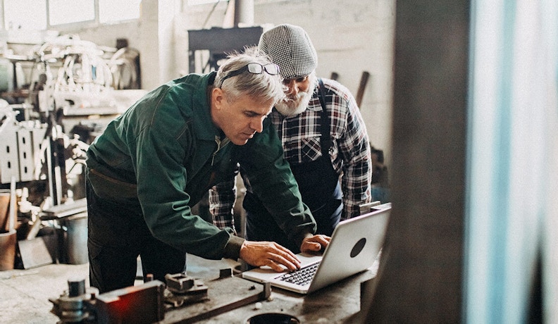 Why ERP is Essential for Small Manufacturing Shops Small manufacturing shop technicians reviewing ERP data on their laptop