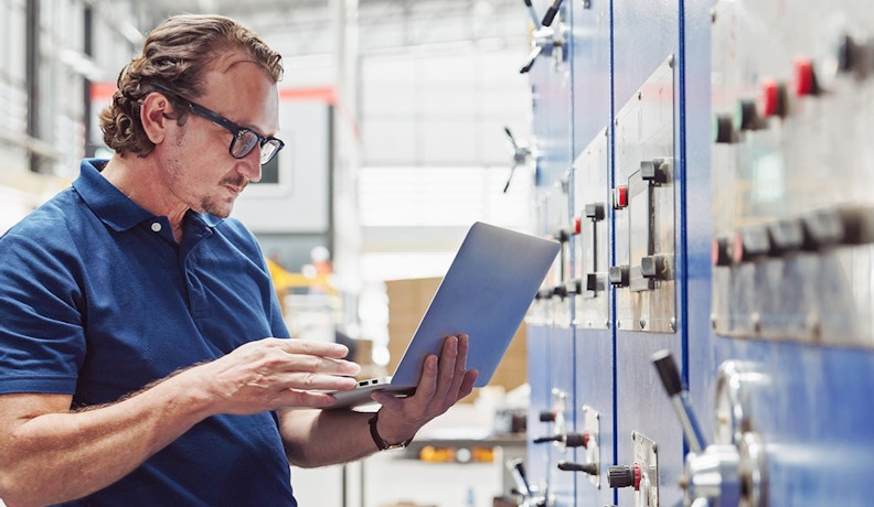 Enhancing Production Processes with Real-Time Data Shop floor manager viewing data on a real-time production process optimization dashboard on a manufacturing shop floor