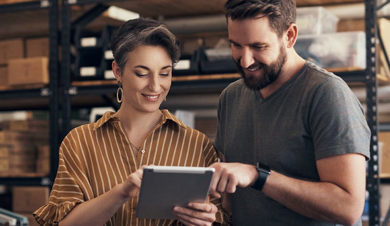 Retail ERP Solutions for Team Collaboration Two retail professionals using a tablet to manage inventory with ERP solutions.