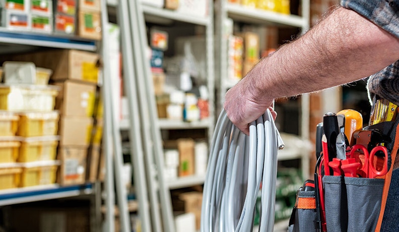 Essential B2B Ecommerce Features for Trade Distributors A trade professional in a warehouse holding electrical cable with tools at their side, illustrating supply access and logistics for B2B ecommerce.