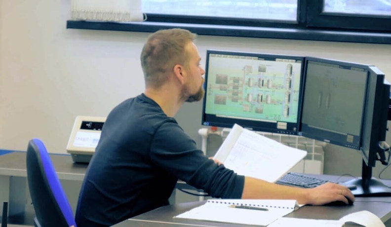 All-in-One Field Service Software Dashboard in Use Technician reviewing schematics while using all-in-one field service software on dual monitors in an office.