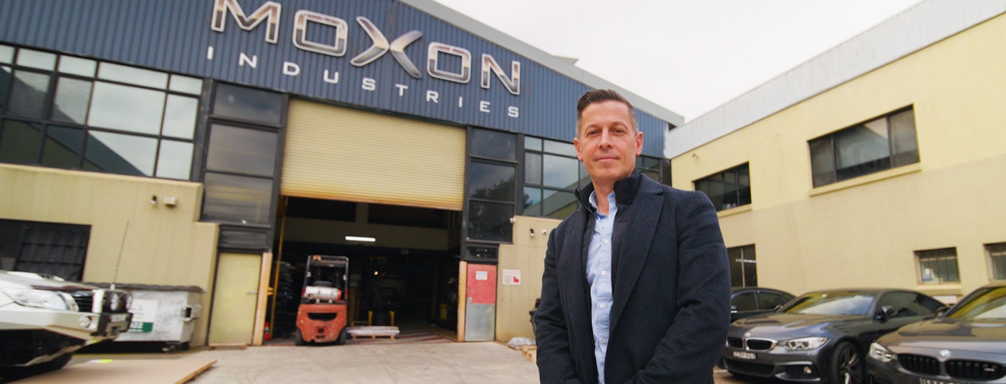 Moxon Industries ERP Success with M1 System A business professional stands in front of Moxon Industries' factory, representing their M1 ERP success story.