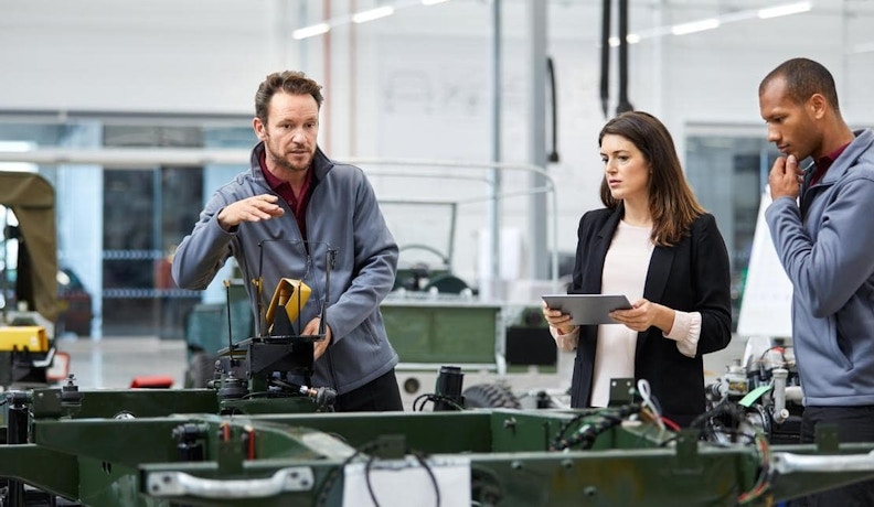 Manufacturing Execution System Three manufacturing employees coordinating schedules on a centralized platform for efficient resource planning and real-time staffing adjustments