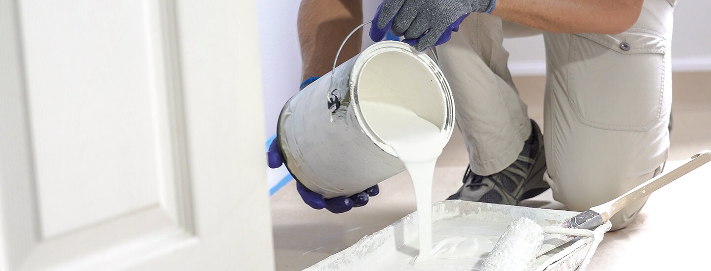 Painting contractor pouring paint into a rolling pan