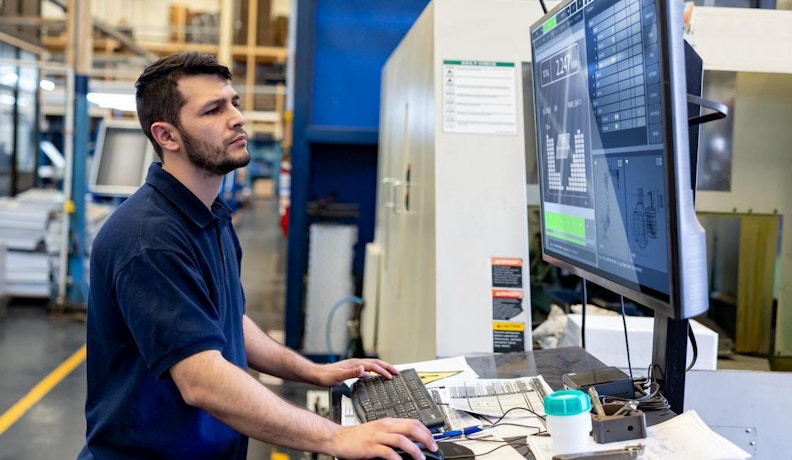 CMMC compliance 2025 Job shop tech reviewing CMMC compliance information on a floor monitor