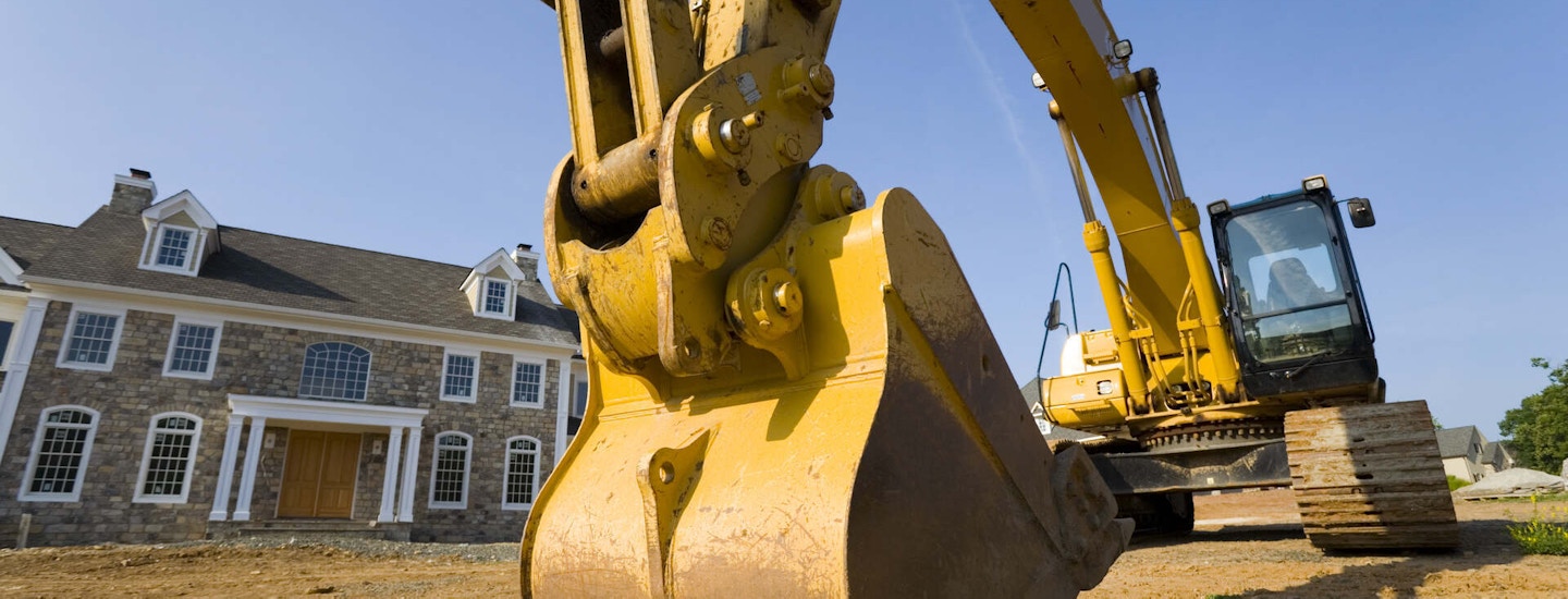 Excavator parked in front of a newly constructed home
