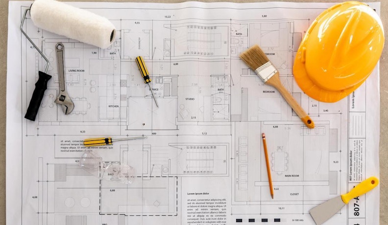 BuildTools Financial Control in Construction Projects Blueprints lying on a construction site while remodeling a house - home improvement concepts
