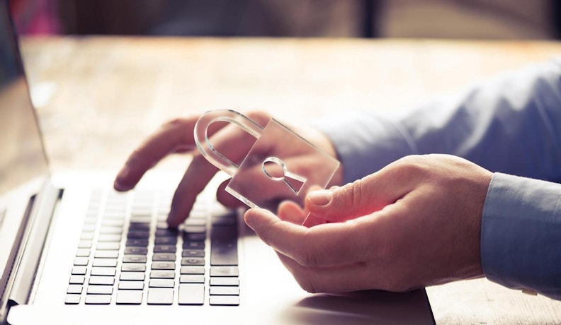 CUI for CMMC Compliance: Data Security and Protection Person holding a transparent padlock over a laptop, symbolizing CUI protection for CMMC compliance.