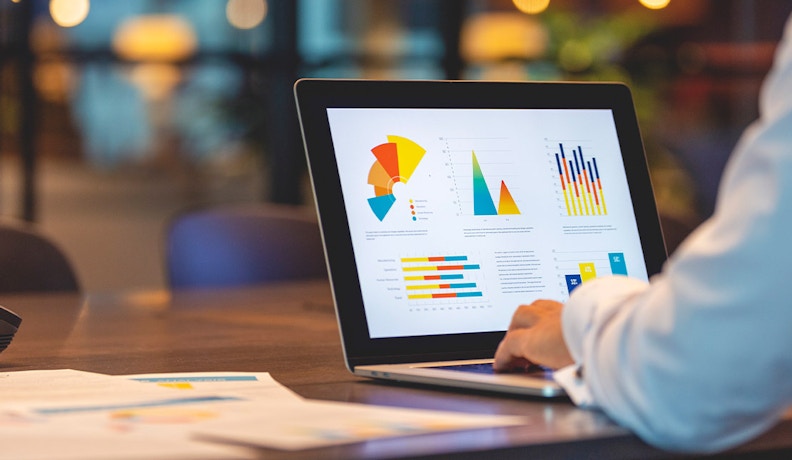 ERP Dashboards for Executives: Visual Data Insights An executive analyzing colorful ERP dashboard charts on a laptop, displaying key performance metrics and business data.