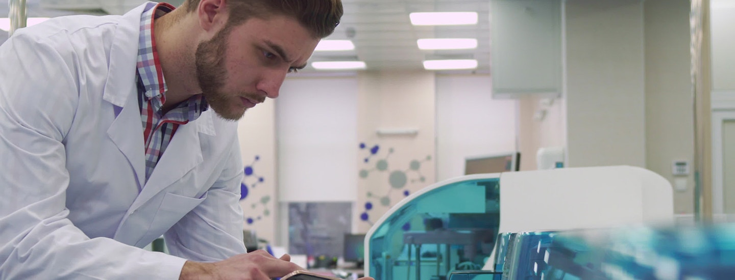 Medical Device ERP Software Integration in Laboratory A lab technician uses a tablet to monitor medical devices, illustrating ERP software integration in a clinical lab.