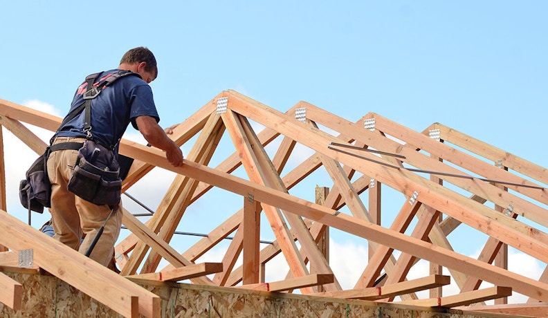 New Home Builder Survey 2021 Construction worker standing on the roof of an unfinished residential home
