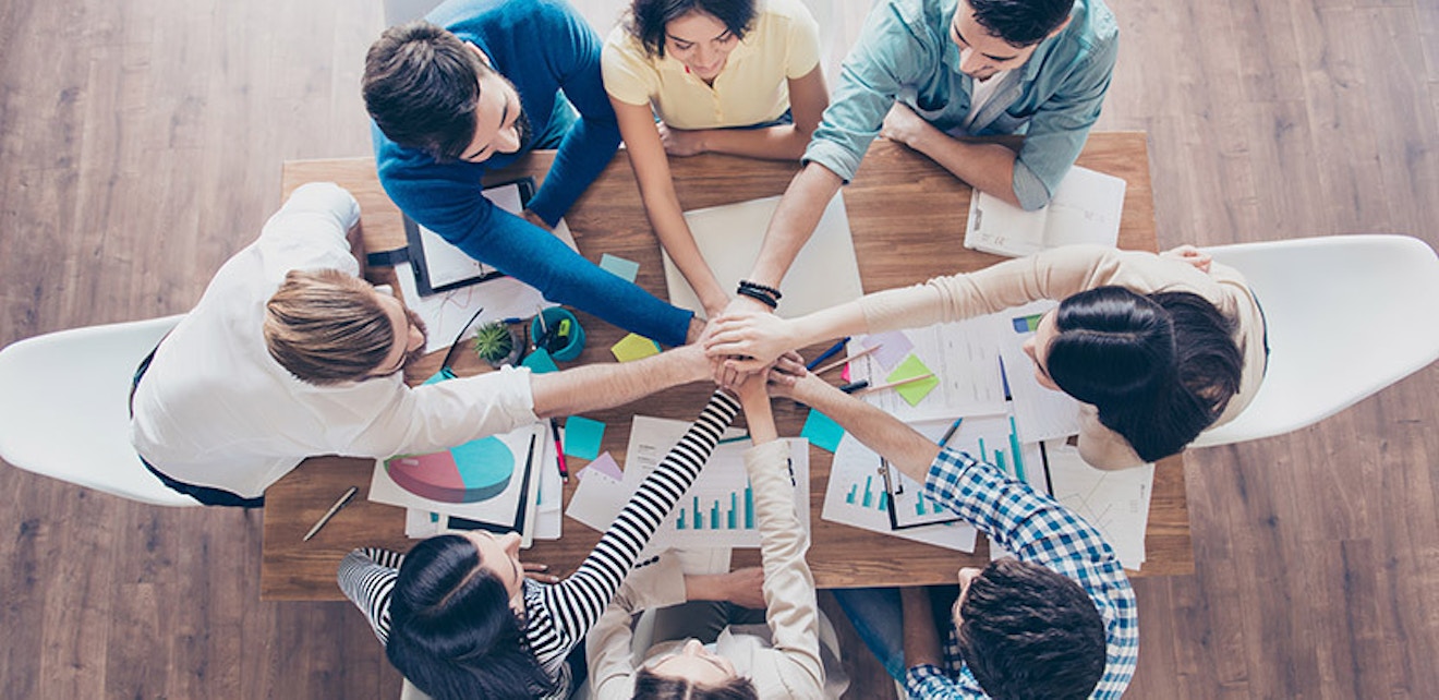 Small business teamwork inspired by Mary Kay's leadership Diverse team putting hands together symbolizing teamwork in small business