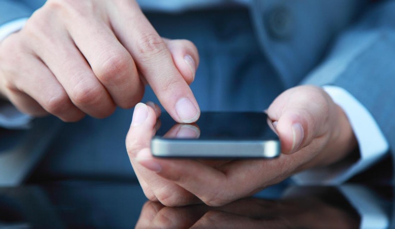 SMS marketing compliance for homebuilders Man texting on a mobile phone.